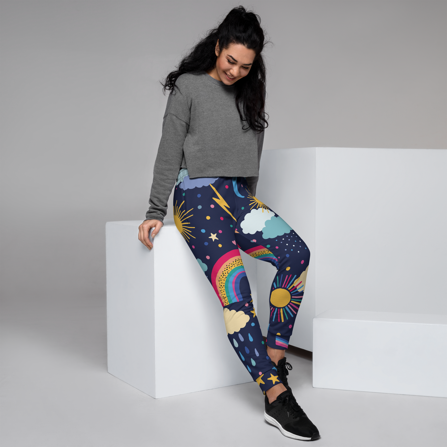 Navy joggers with rainbow, sun, and cloud pattern throughout the fabric.