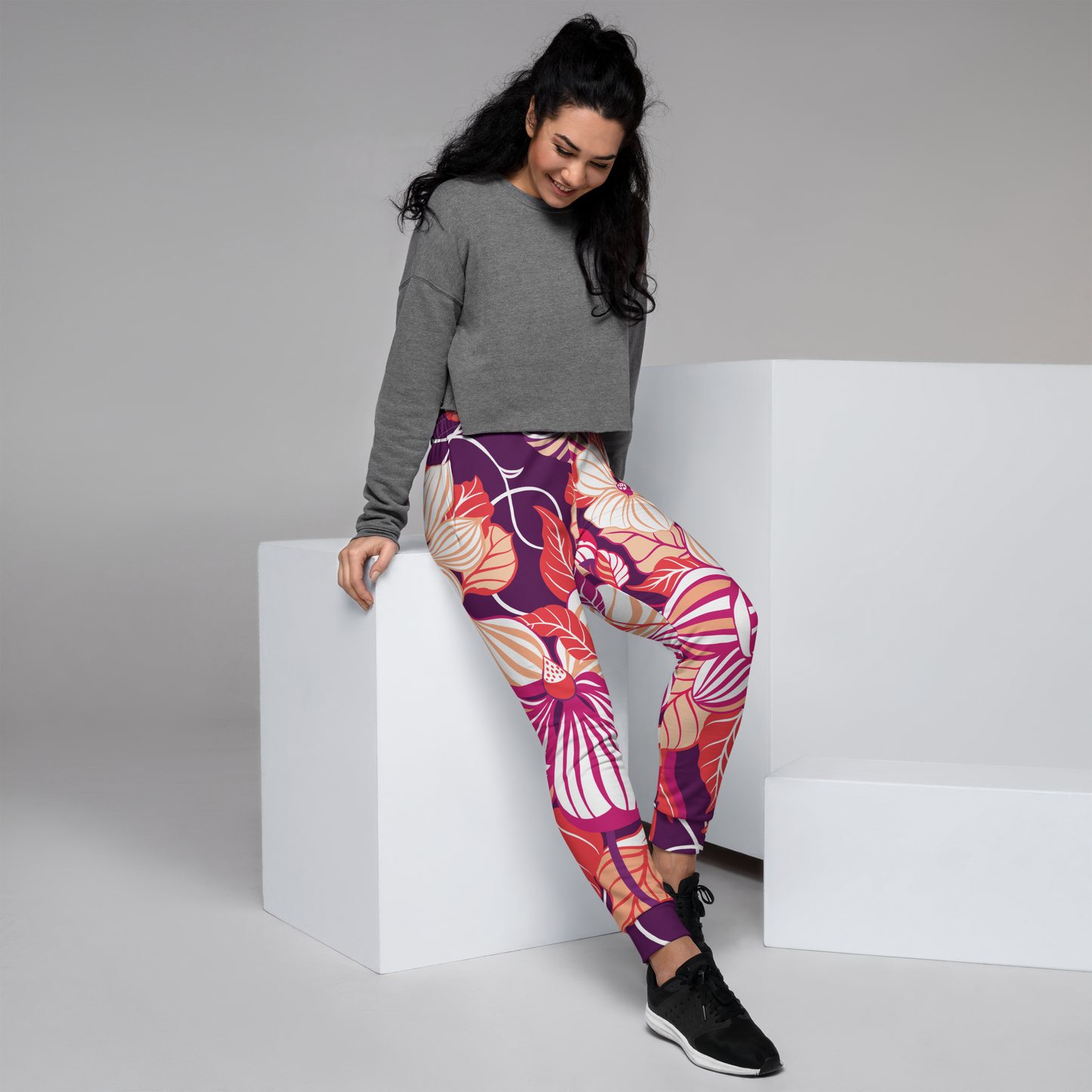 Women's joggers with oversized floral print in fuchsia, cream, orange, and purple.