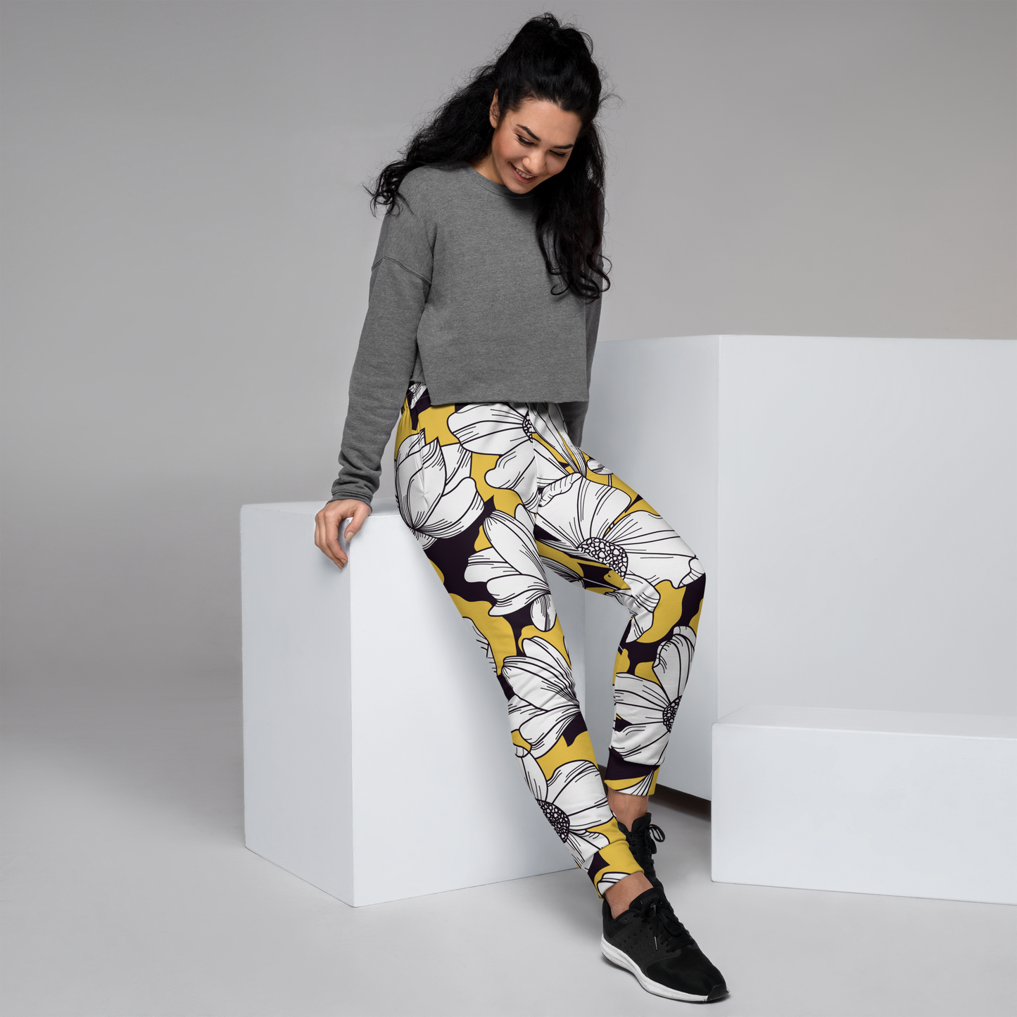 Women's joggers with oversized white daisy print on vivid yellow background.