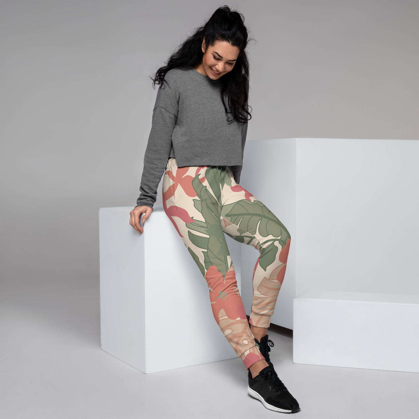Pastel floral leaf print joggers in muted pink and green on beige background.